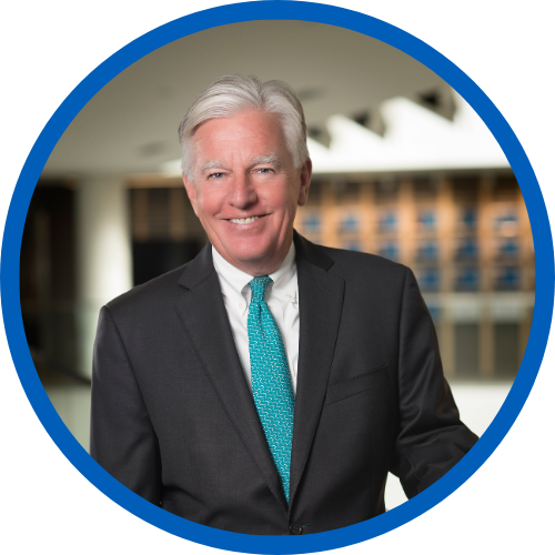 president meehan in a dark suit with a teal tie standing in front of a building at UMass Lowell